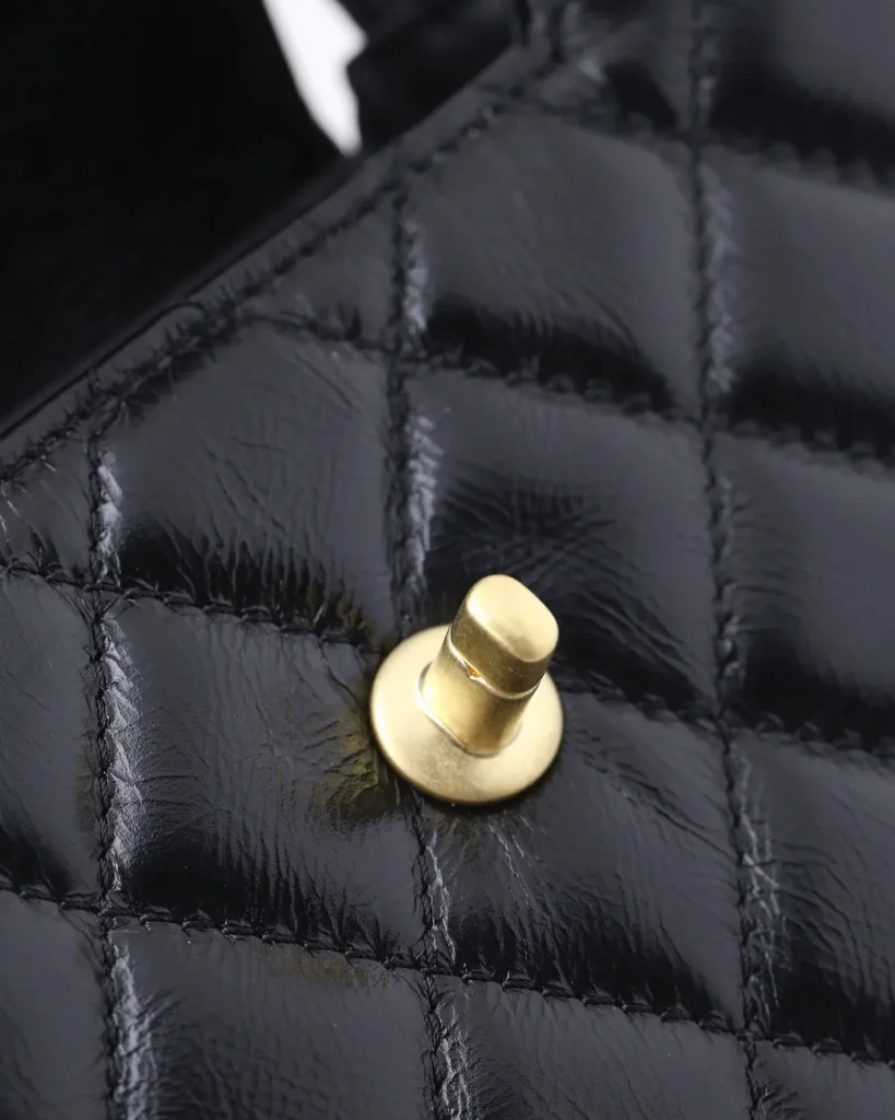 Black Quilted Tab-Flap Top-Handle Bag — closure detail view