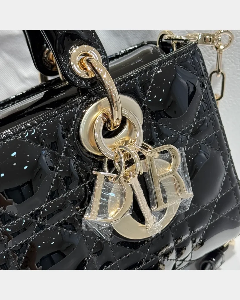 Glossy Black Horizontal Quilted Handbag — charm detail view