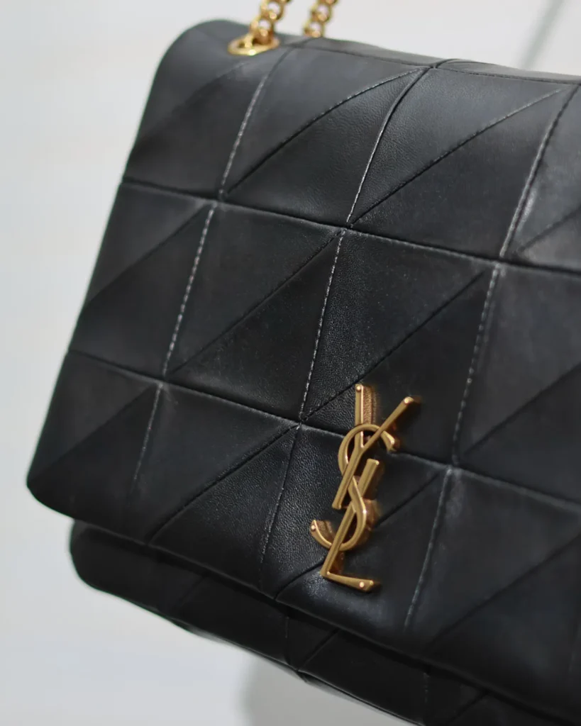 Black Geometric Quilted Flap Bag — emblem detail view