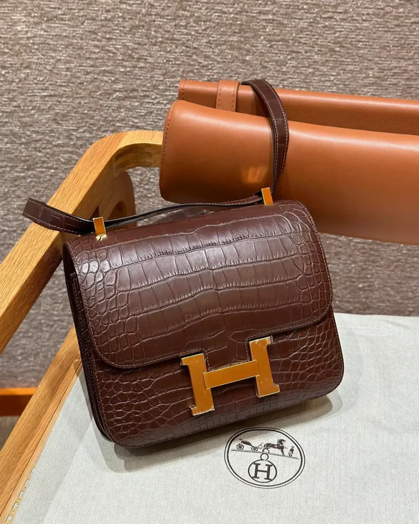 Angled front view of brown scale-texture mini flap bag resting on a chair