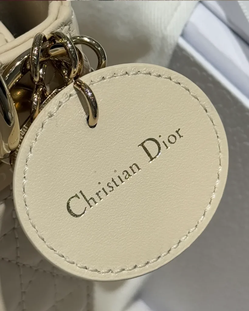 Cream Quilted Top Handle Bag with Sparkling Charms — round tag view