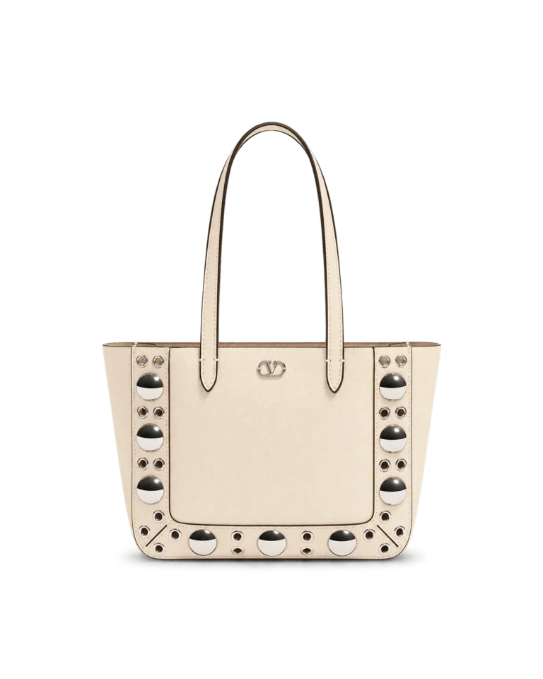 Upright front view of a cream long-handle tote with silver dome studs and circular eyelets