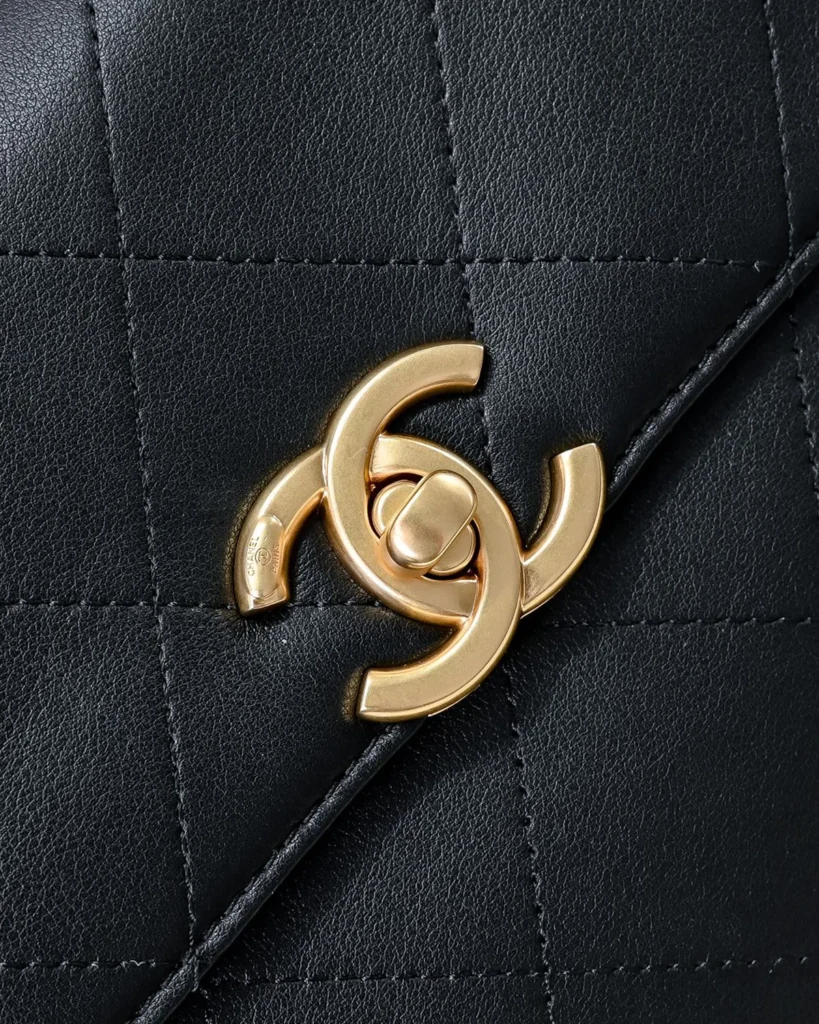 Black Quilted Top-Handle Flap Bag — clasp detail view
