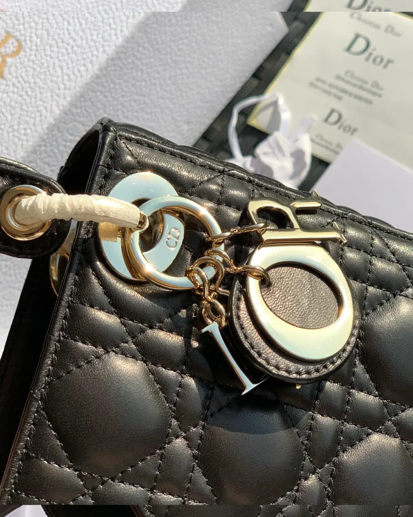Black Quilted Compact Top Handle Bag — charm detail view