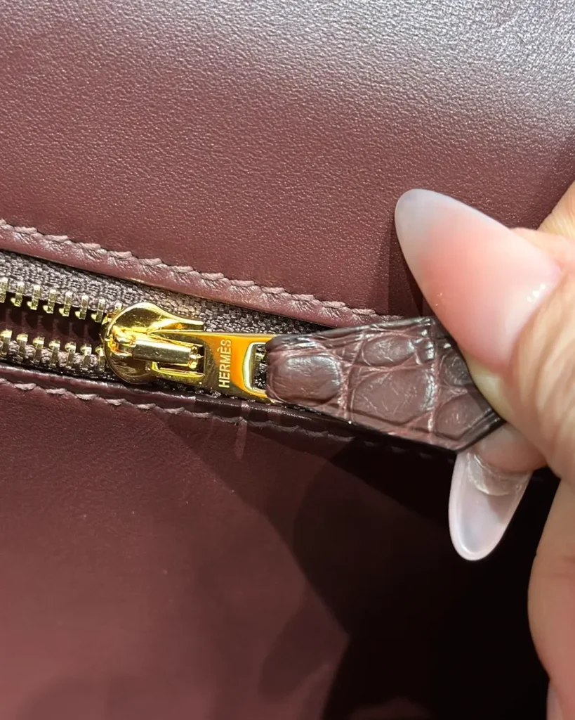 Close-up of gold-tone interior zipper and brown pull tab