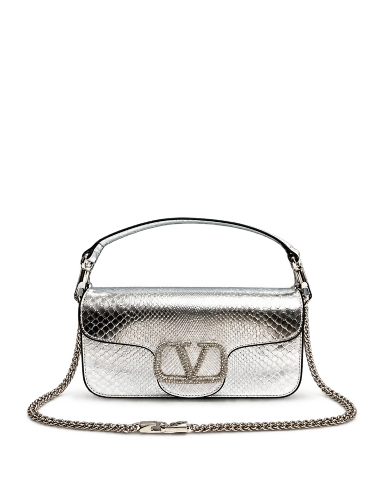 Upright front view of a silver scale-pattern flap bag with an arched top handle, stone-covered emblem and continuous silver shoulder chain