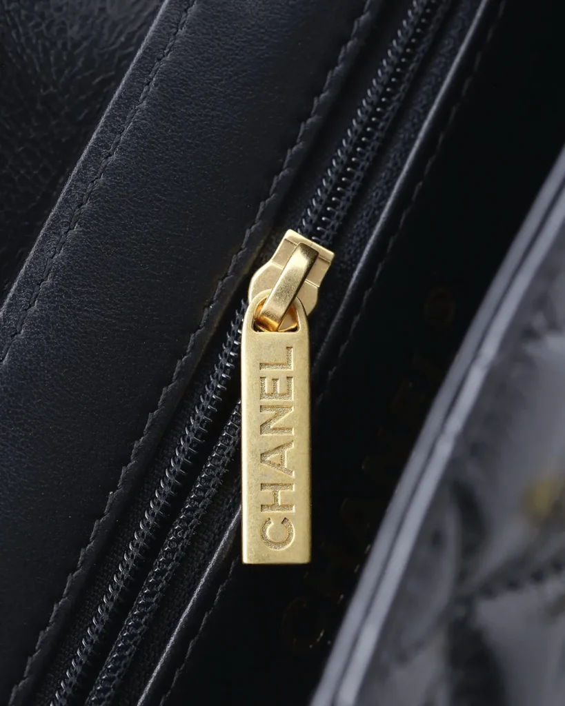 Black Quilted Tab-Flap Top-Handle Bag — zipper detail view
