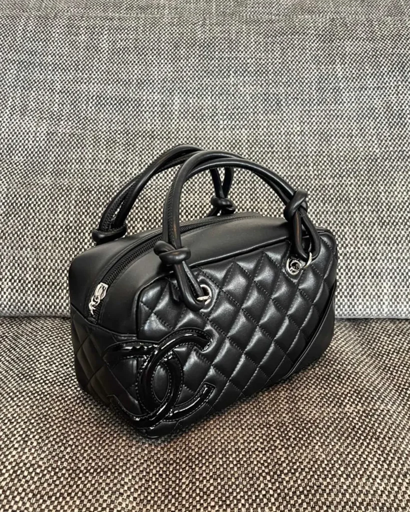 Black Quilted Offset-Emblem Bowler Bag — angled front view
