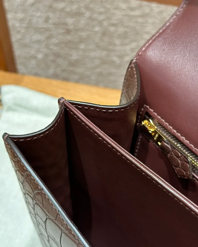 Interior side view of brown mini bag showing center divider, side gusset and zip pocket