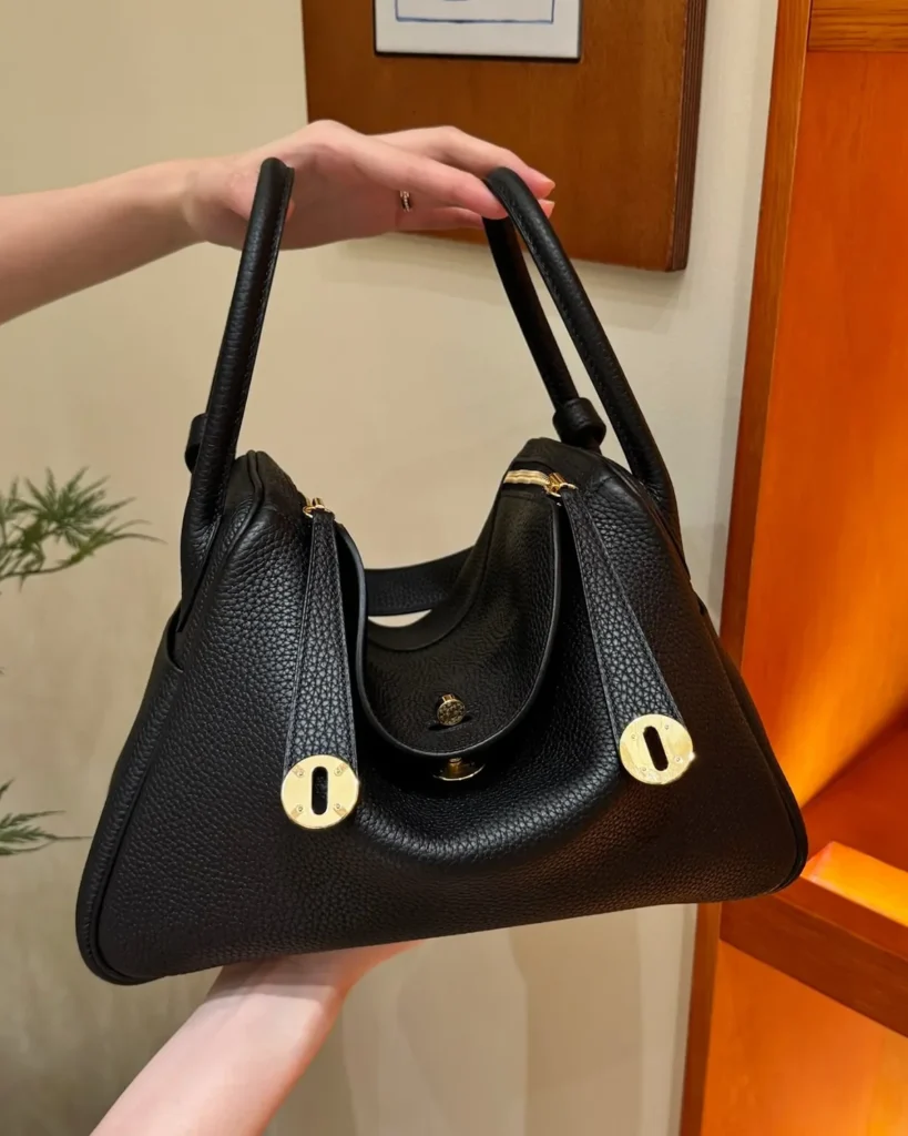 Black Folded Shoulder Bag with Gold-Tone Details — hand carry view