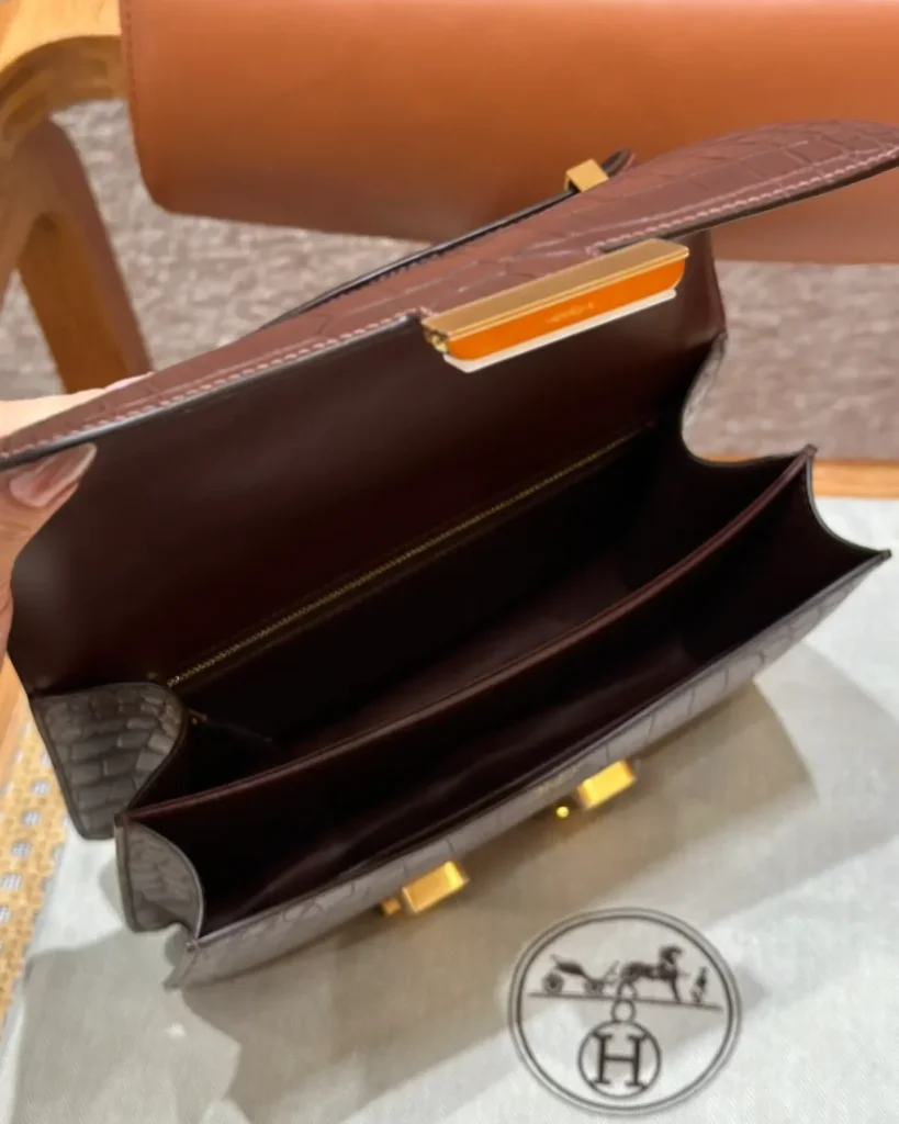 Open brown mini flap bag showing divided compartments and a rear zip pocket