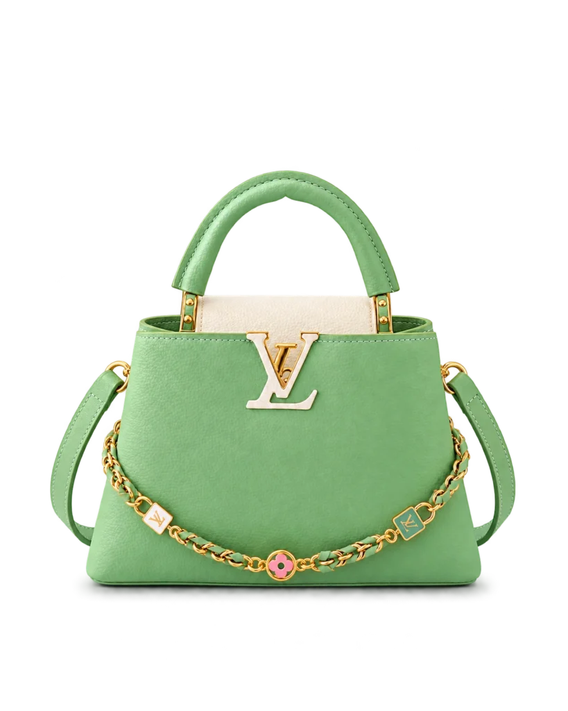 Upright front view of a green and cream top-handle bag with a gold-tone charm chain and green shoulder strap