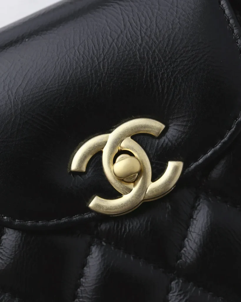 Black Quilted Tab-Flap Top-Handle Bag — logo detail view